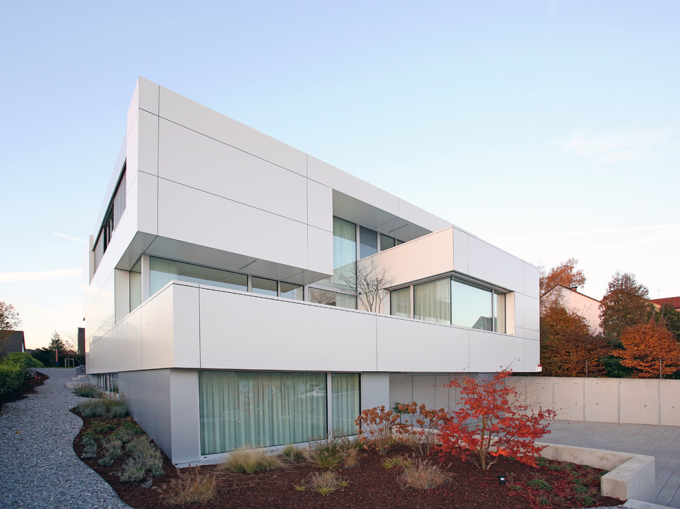 Modelo de fachada blanca contemporánea extra grande a niveles con revestimientos combinados y tejado plano