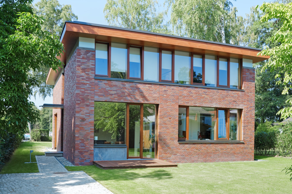 Aménagement d'une façade de maison rouge contemporaine en brique à un étage et de taille moyenne avec un toit plat.