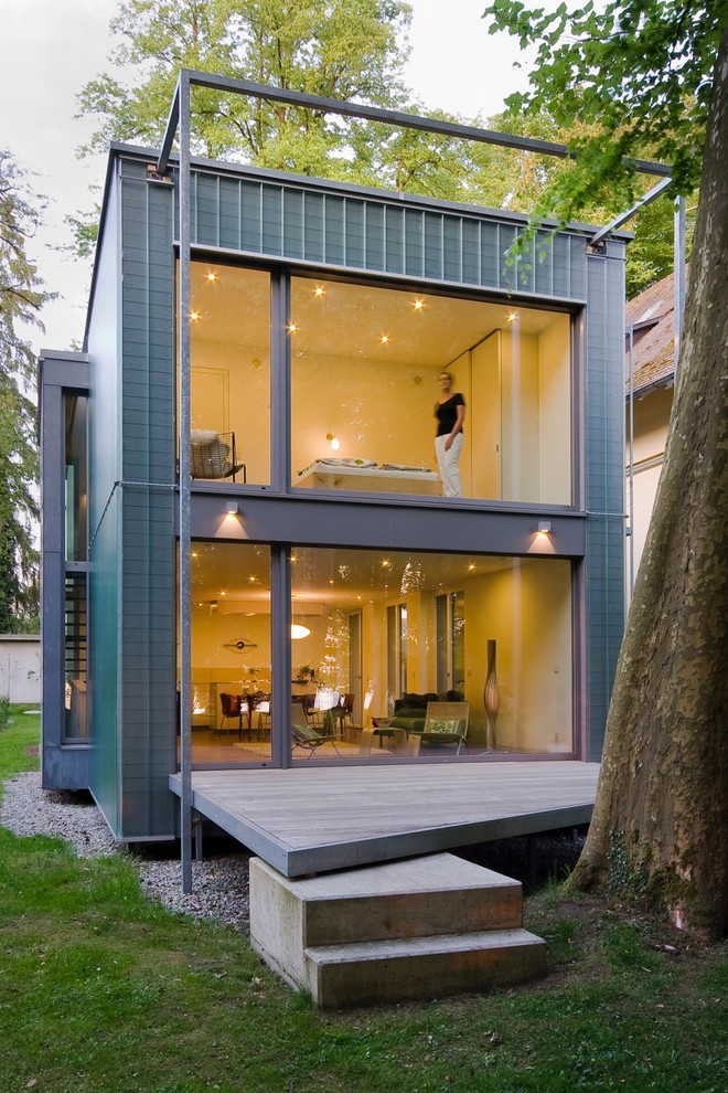 На фото: двухэтажный, серый дом среднего размера в современном стиле с облицовкой из металла и плоской крышей