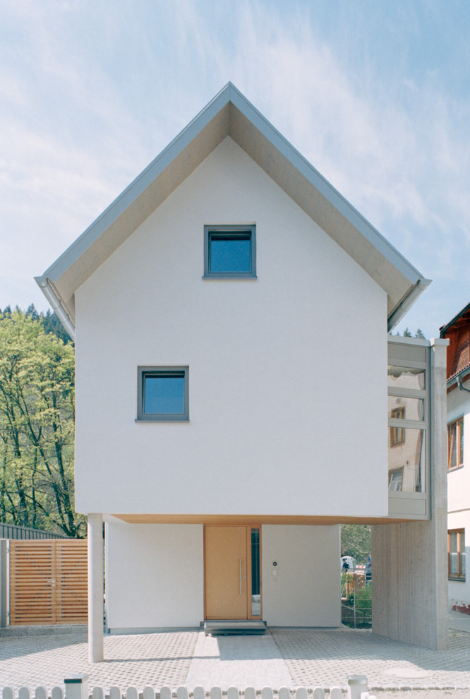 Diseño de fachada blanca contemporánea grande de dos plantas con revestimiento de hormigón y tejado a dos aguas