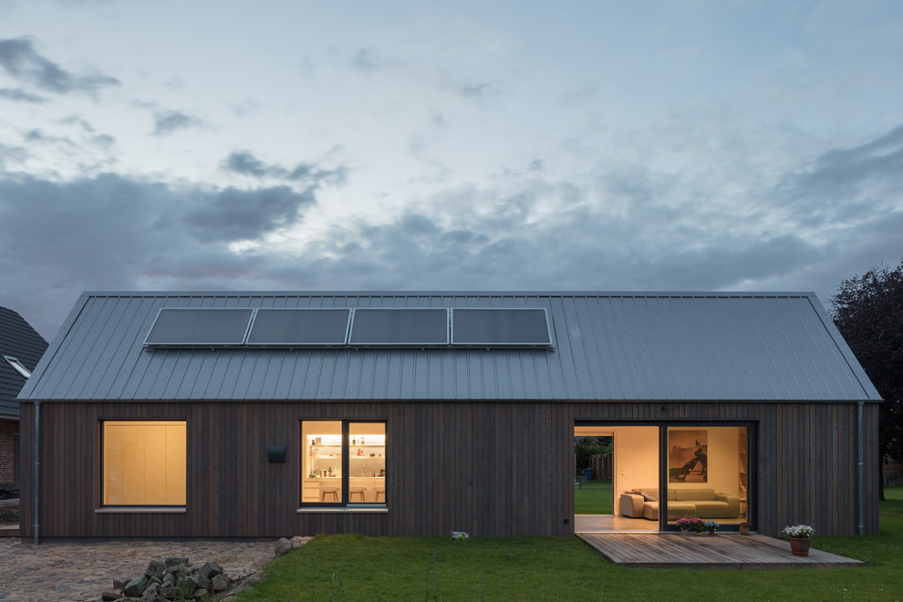 Идея дизайна: одноэтажный, деревянный, коричневый частный загородный дом среднего размера в скандинавском стиле с двускатной крышей и металлической крышей