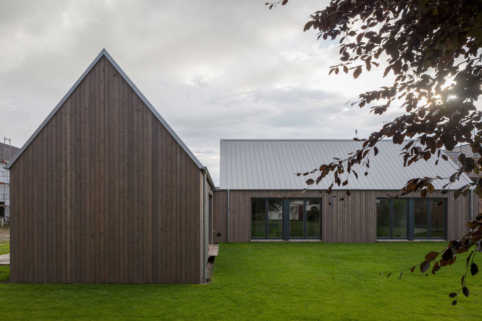 Ejemplo de fachada de casa marrón nórdica de tamaño medio de una planta con revestimiento de madera, tejado a dos aguas y tejado de metal