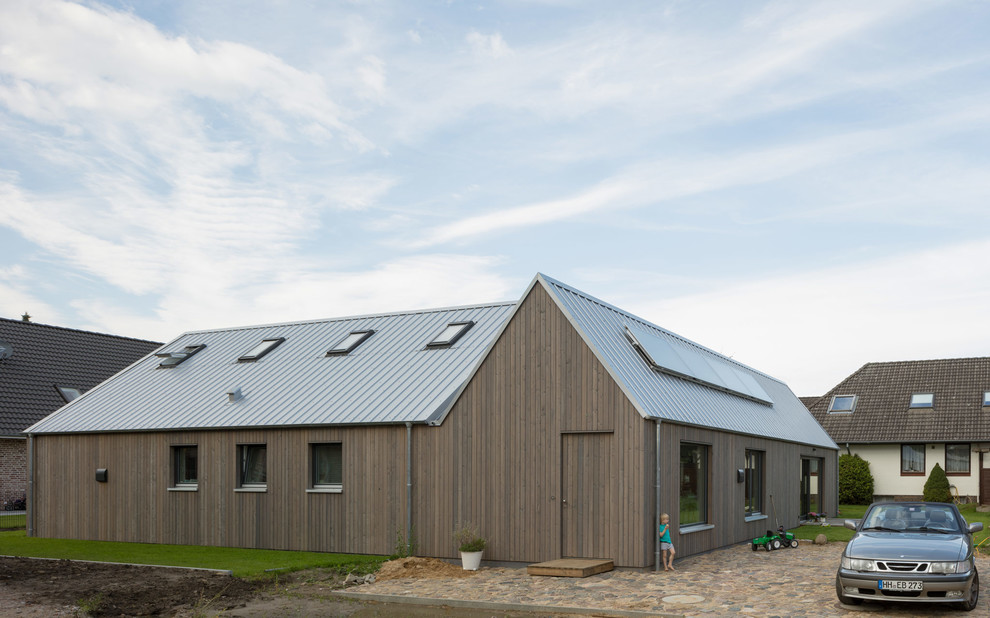 Immagine della villa marrone scandinava a un piano con rivestimento in legno, tetto a capanna e copertura in metallo o lamiera