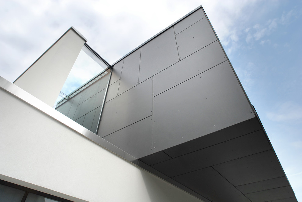 Imagen de fachada de casa gris minimalista de tamaño medio a niveles con revestimiento de aglomerado de cemento y tejado plano