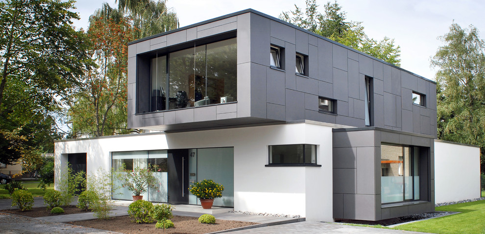 Diseño de fachada de casa blanca moderna de tamaño medio a niveles con revestimientos combinados y tejado plano