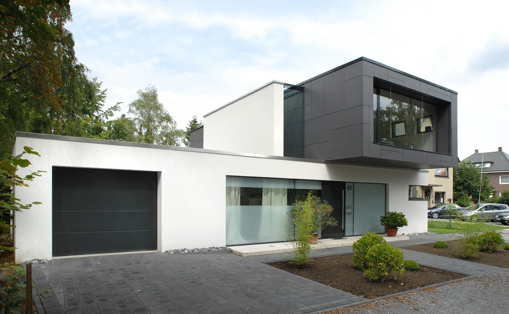 Mittelgroßes Modernes Einfamilienhaus mit Putzfassade, weißer Fassadenfarbe und Flachdach in Sonstige