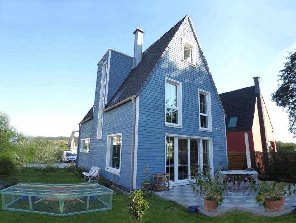 Aménagement d'une façade de maison bleue scandinave en bois de taille moyenne et à un étage avec un toit en tuile.