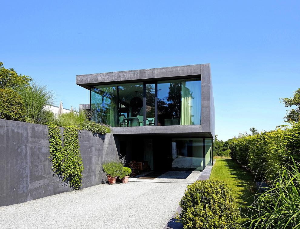Cette image montre une façade de maison grise minimaliste en béton à un étage et de taille moyenne avec un toit plat.