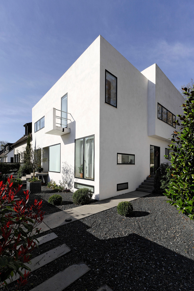 Ejemplo de fachada blanca minimalista de tamaño medio de dos plantas con revestimiento de estuco