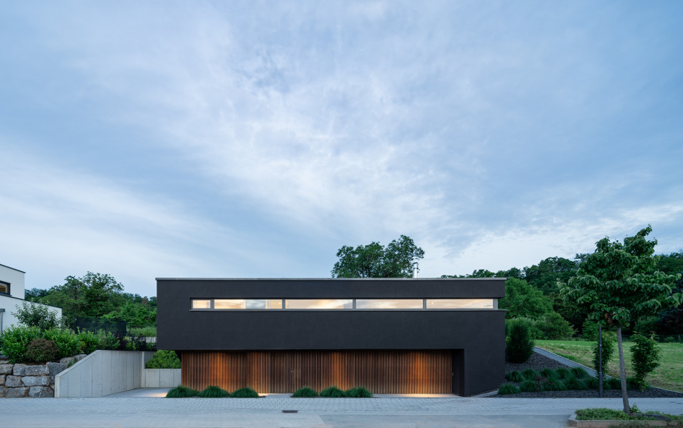 Immagine della villa nera moderna a due piani di medie dimensioni con rivestimento in legno, tetto piano e copertura verde