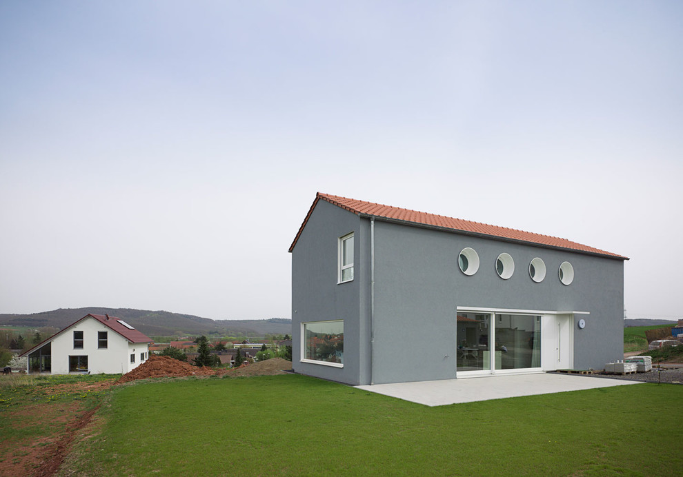 Источник вдохновения для домашнего уюта: двухэтажный, серый дом среднего размера в современном стиле с двускатной крышей и облицовкой из цементной штукатурки