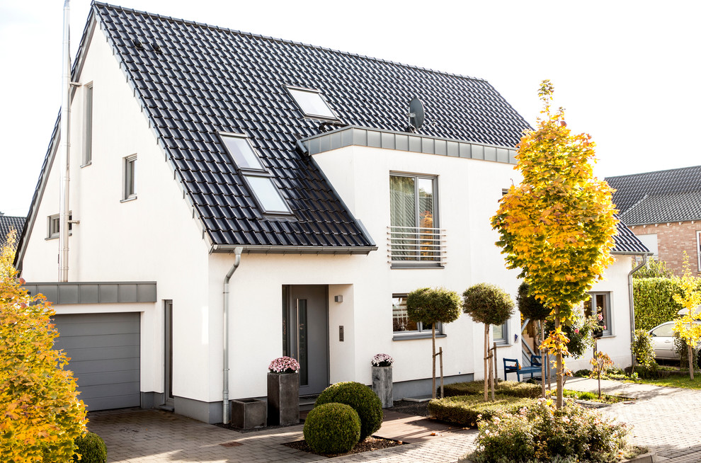 Mittelgroße, Zweistöckige Moderne Doppelhaushälfte mit weißer Fassadenfarbe, Satteldach, Putzfassade, Ziegeldach, schwarzem Dach und Dachgaube in Düsseldorf