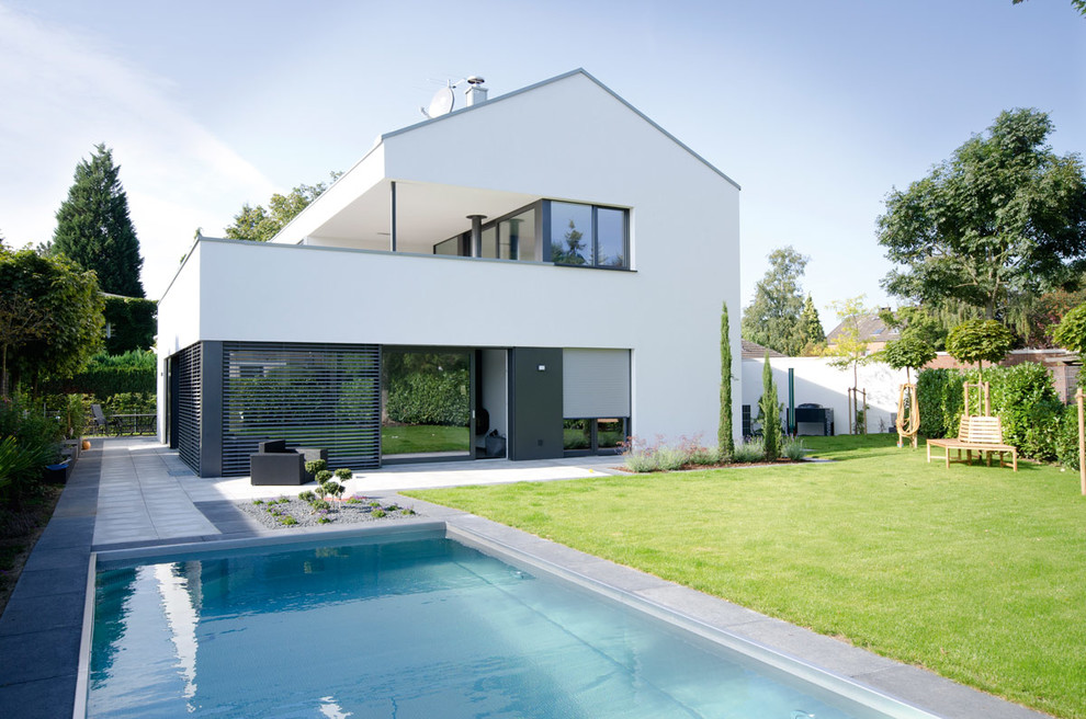 Photo of a large and white contemporary two floor house exterior in Cologne with a pitched roof.