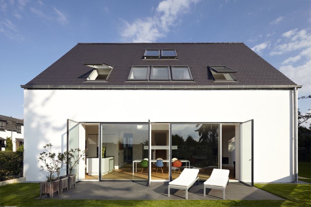 Photo of a large and white contemporary house exterior in Cologne with three floors and a pitched roof.