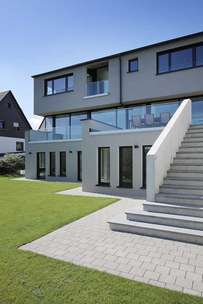 Großes, Dreistöckiges Modernes Einfamilienhaus mit Putzfassade, grauer Fassadenfarbe und Flachdach