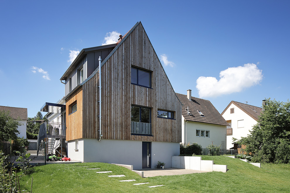 Modelo de fachada de casa marrón actual de tamaño medio de tres plantas con revestimientos combinados y tejado a dos aguas
