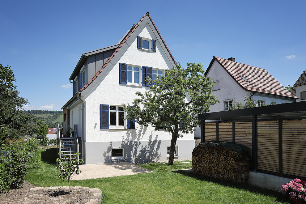 Imagen de fachada de casa blanca actual de tamaño medio de tres plantas con revestimiento de estuco, tejado a dos aguas y tejado de teja de barro