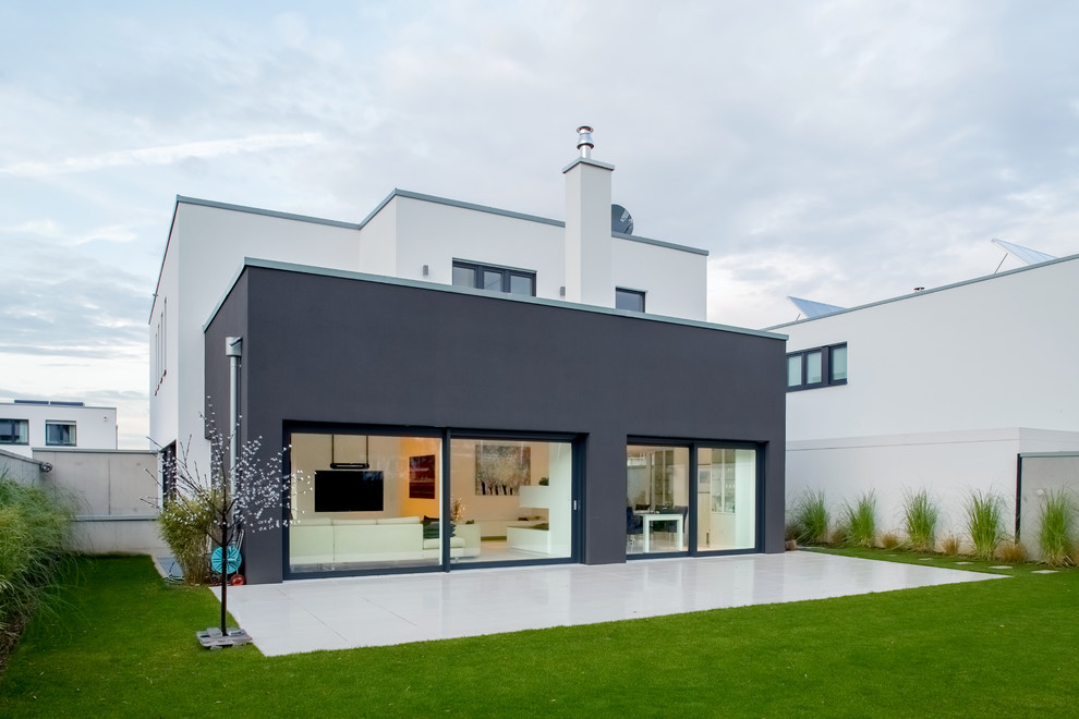 Immagine della facciata di una casa grande nera contemporanea a due piani con rivestimento in stucco e tetto piano