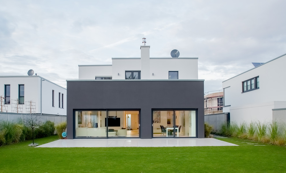 Immagine della facciata di una casa grande nera contemporanea a due piani con rivestimento in stucco e tetto piano