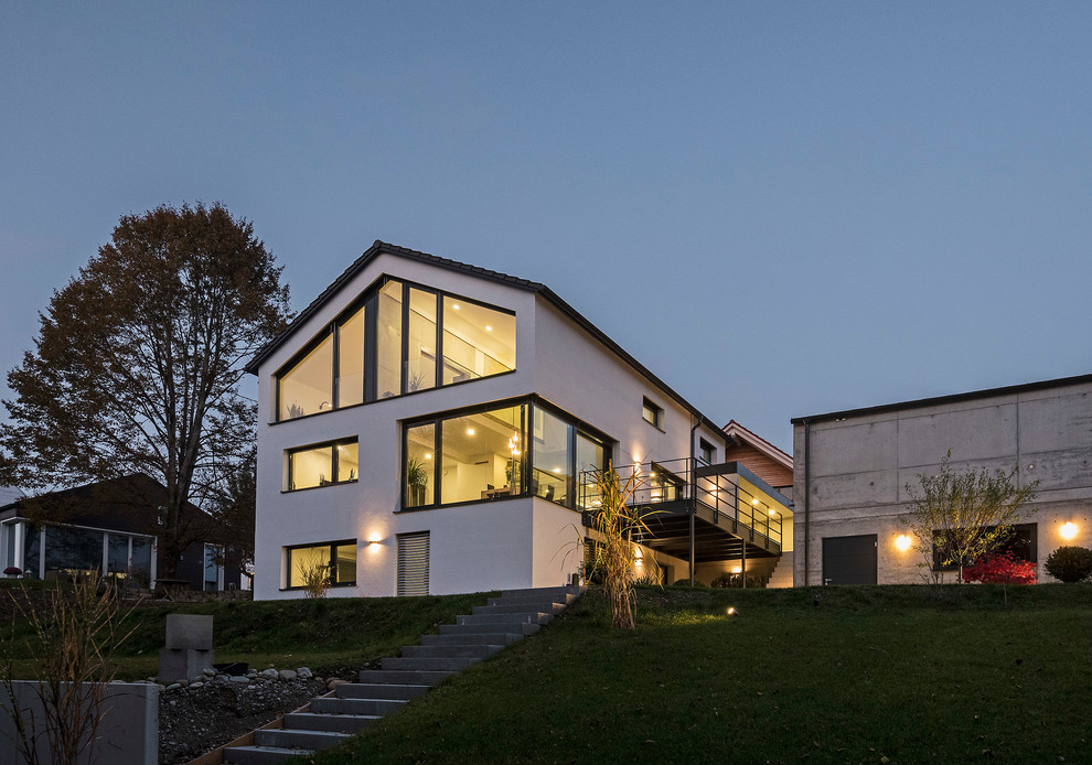 Свежая идея для дизайна: белый дом среднего размера в современном стиле с облицовкой из бетона и двускатной крышей - отличное фото интерьера