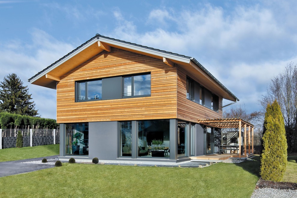 Пример оригинального дизайна: двухэтажный, коричневый частный загородный дом в современном стиле с комбинированной облицовкой, двускатной крышей и черепичной крышей