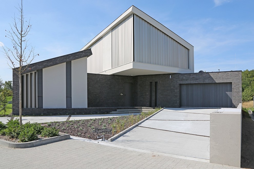 Imagen de fachada gris actual extra grande a niveles con revestimientos combinados y tejado de un solo tendido