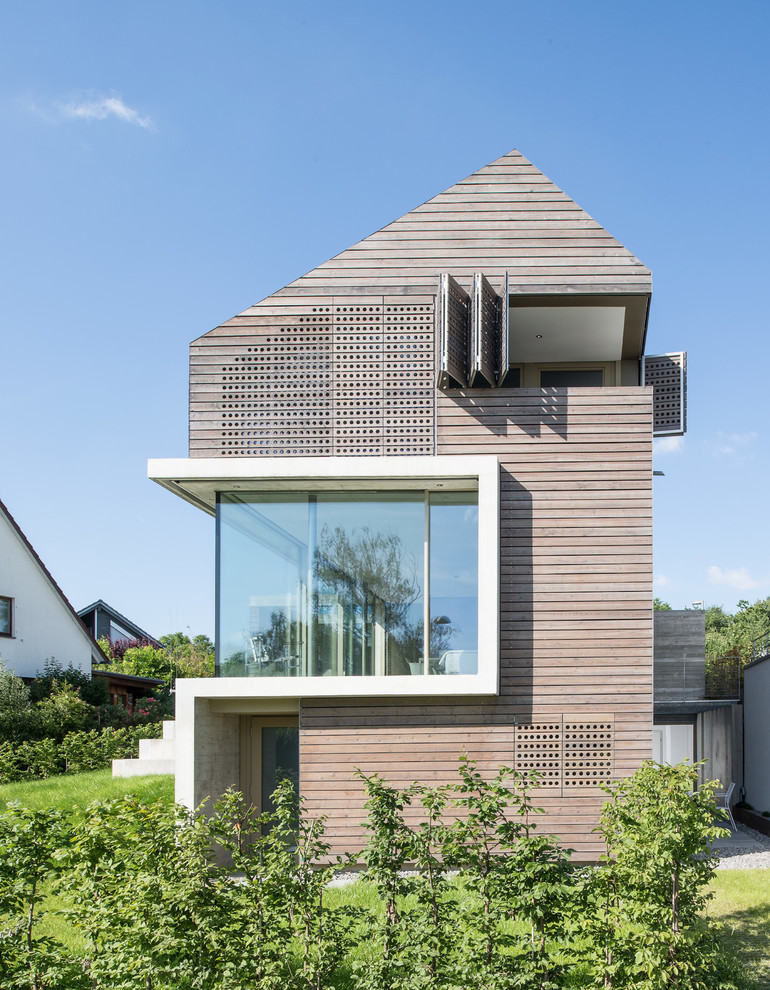 Inspiration for a beige contemporary detached house in Essen with three floors and wood cladding.