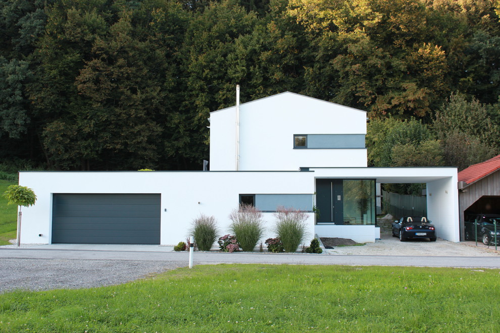 На фото: большой, белый дом в современном стиле с разными уровнями и двускатной крышей с