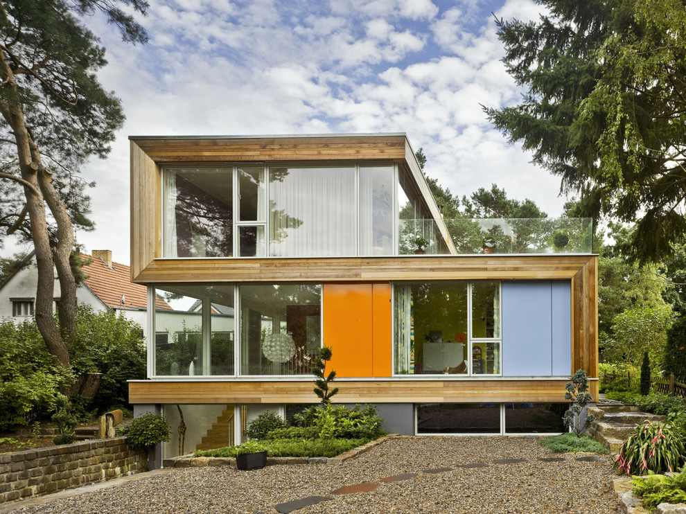 Ejemplo de fachada marrón moderna de tres plantas con revestimiento de madera y tejado plano