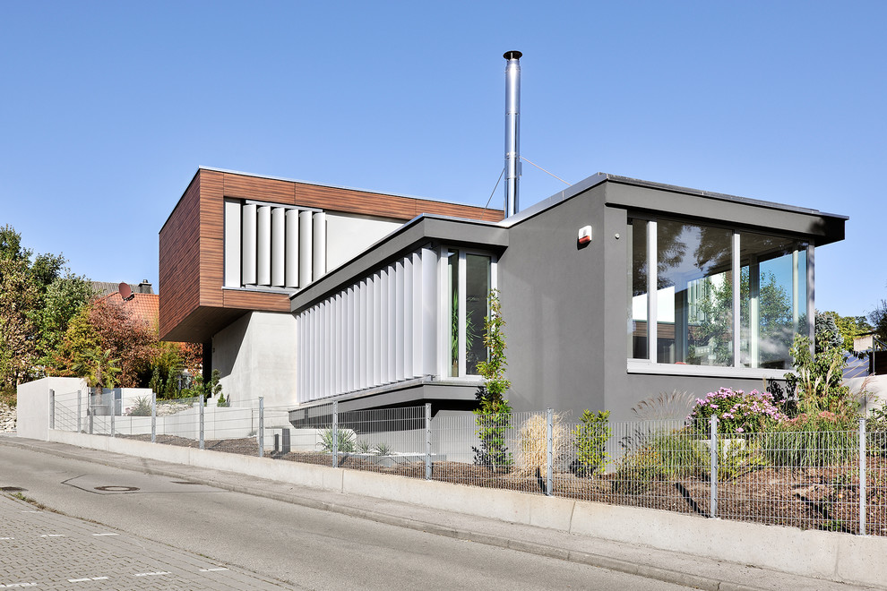Imagen de fachada de casa gris actual de tamaño medio de dos plantas con revestimiento de hormigón y tejado plano