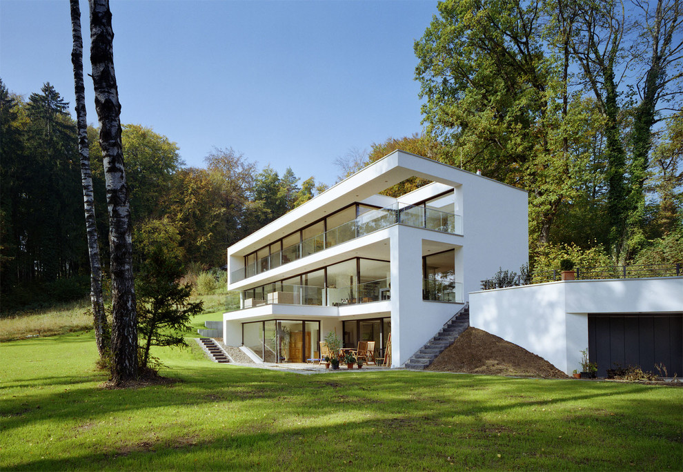 Foto på ett stort funkis vitt hus, med tre eller fler plan och platt tak