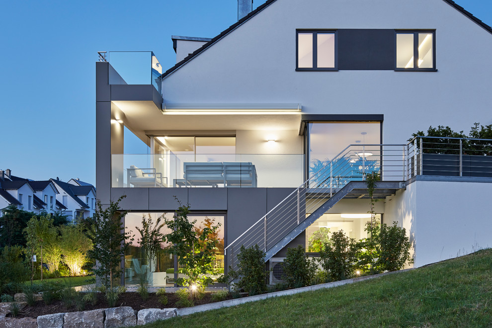 Diseño de fachada de casa blanca moderna grande de tres plantas con revestimiento de estuco y tejado a dos aguas
