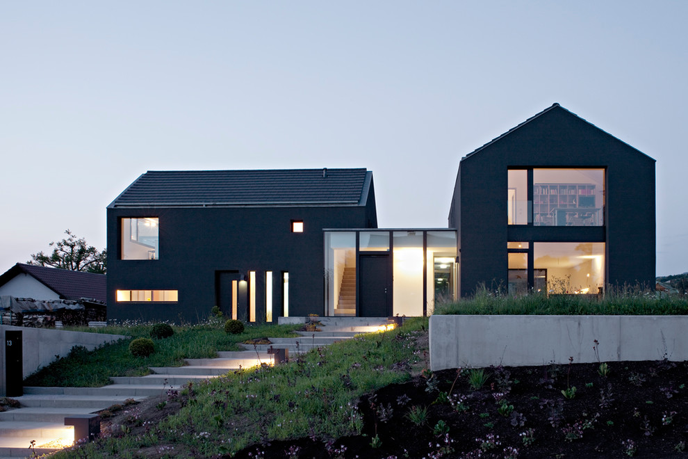 Идея дизайна: двухэтажный, серый частный загородный дом среднего размера в современном стиле с облицовкой из цементной штукатурки, двускатной крышей и крышей из гибкой черепицы
