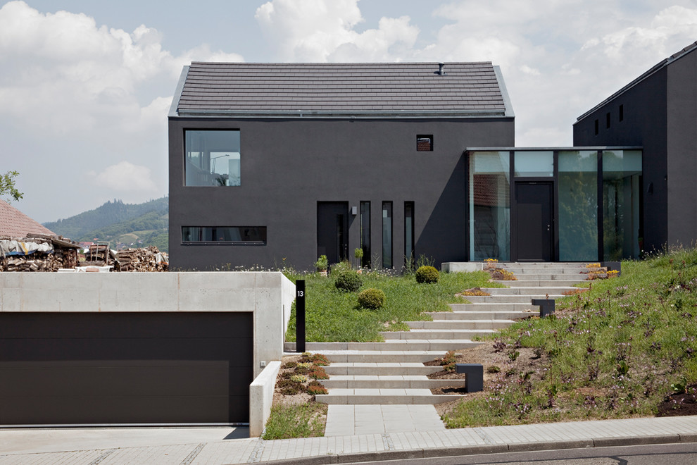 Imagen de fachada gris moderna pequeña de dos plantas con revestimiento de estuco, tejado a dos aguas y tejado de teja de madera