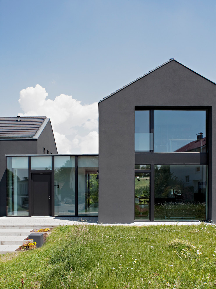 Foto de fachada gris moderna de tamaño medio de dos plantas con revestimiento de estuco, tejado a dos aguas y tejado de teja de madera