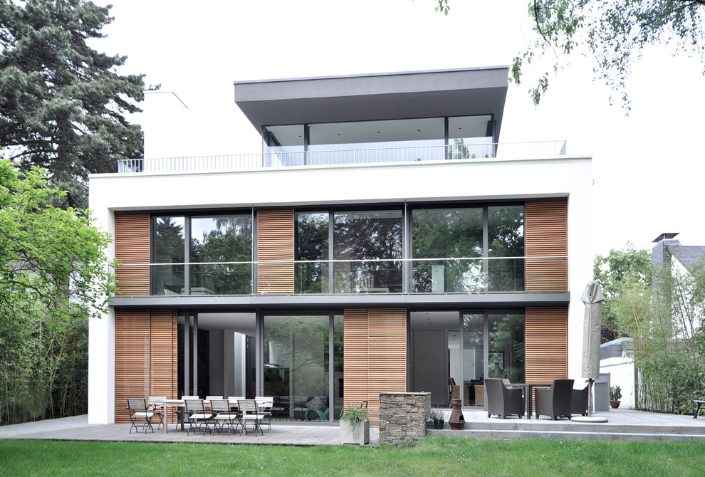 Photo of an expansive and white contemporary two floor house exterior in Dusseldorf with a flat roof and mixed cladding.