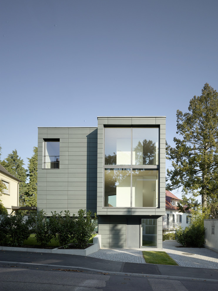 Foto på ett stort funkis grått hus, med tre eller fler plan och platt tak