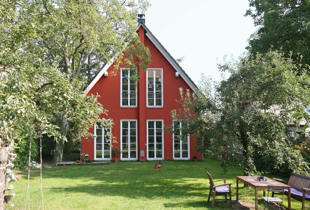 Idée de décoration pour une façade de maison rouge champêtre en stuc de taille moyenne et à un étage avec un toit à deux pans et un toit en tuile.