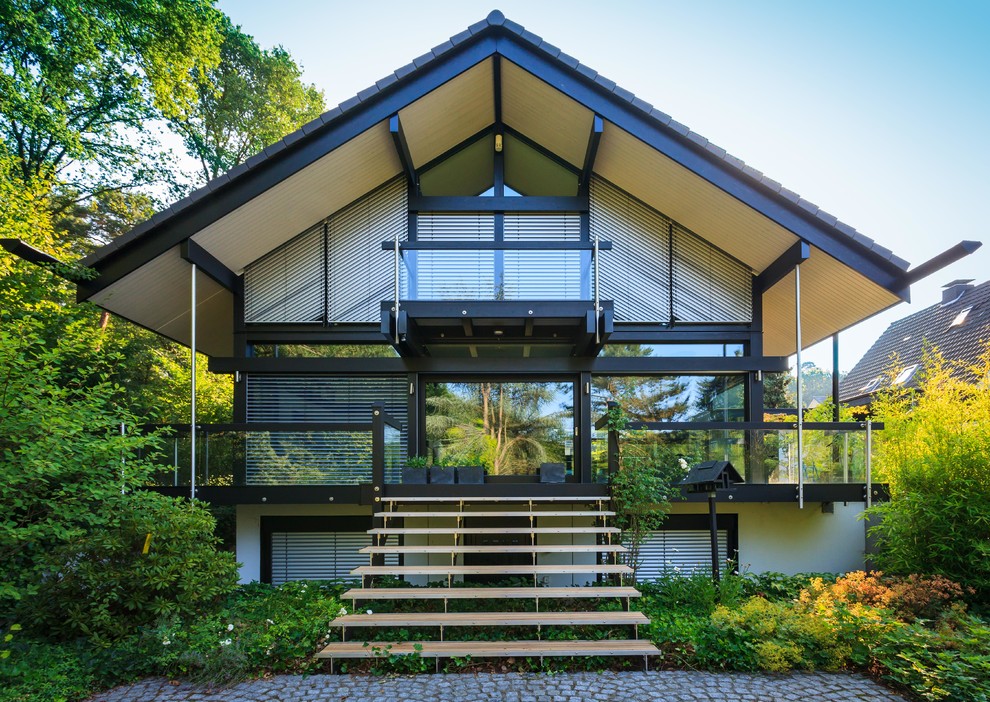 Aménagement d'une façade de maison noire contemporaine en verre à un étage avec un toit à deux pans et un toit en shingle.