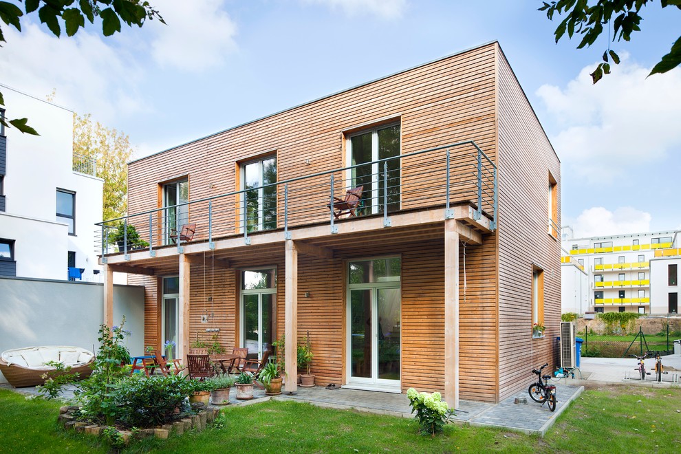 Modelo de fachada de casa marrón nórdica de tamaño medio de dos plantas con revestimiento de madera y tejado plano