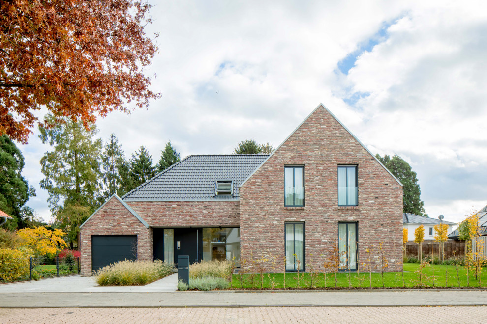 Idée de décoration pour une façade de maison multicolore design en brique de taille moyenne et de plain-pied avec un toit à deux pans, un toit en tuile et un toit noir.