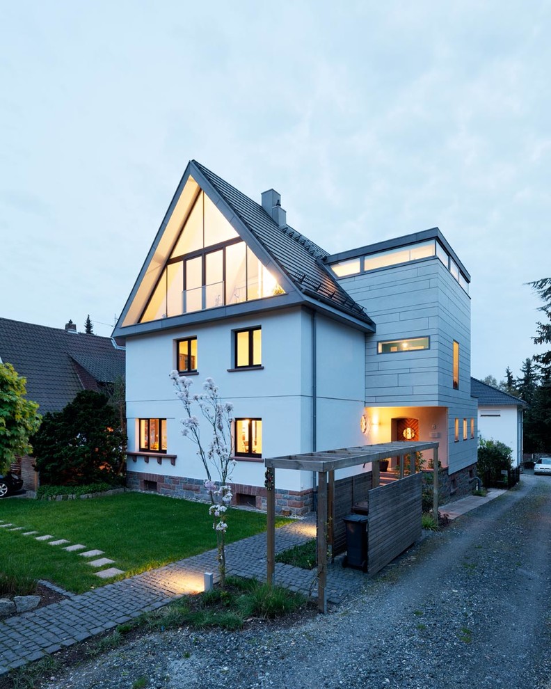 Diseño de fachada blanca contemporánea grande de tres plantas con revestimientos combinados y tejado a dos aguas