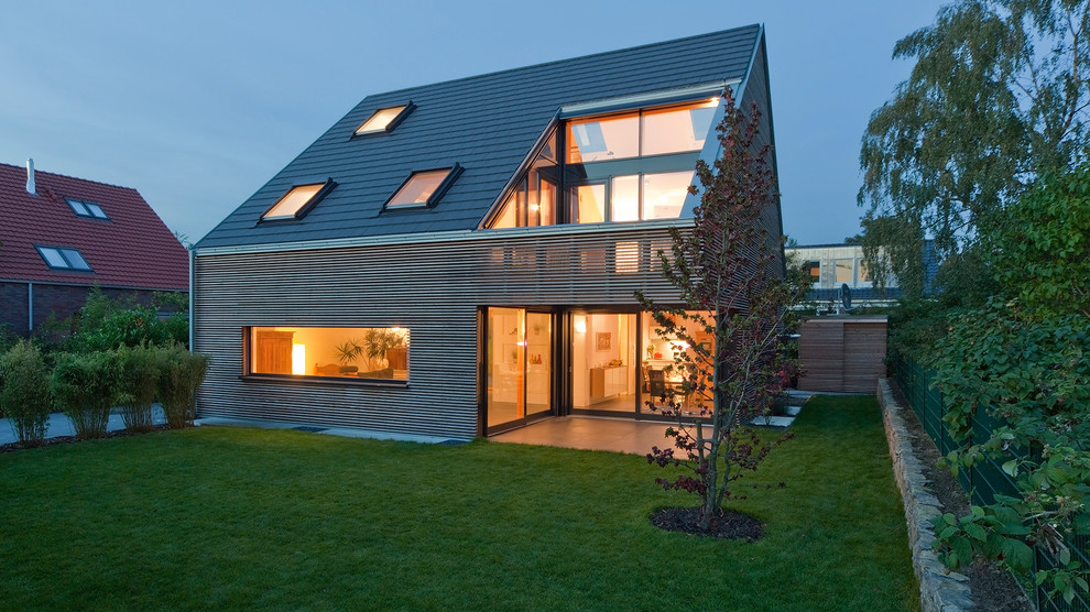 Imagen de fachada de casa marrón actual de tamaño medio de dos plantas con revestimiento de madera, tejado a dos aguas y tejado de teja de madera