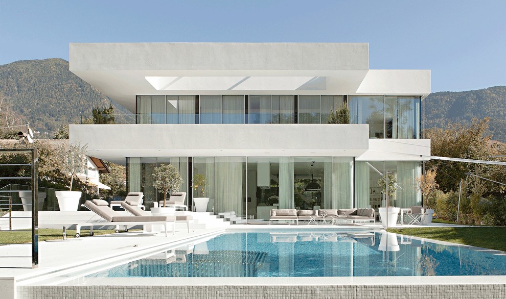 Photo of a white and large contemporary two floor glass house exterior in Other with a flat roof.