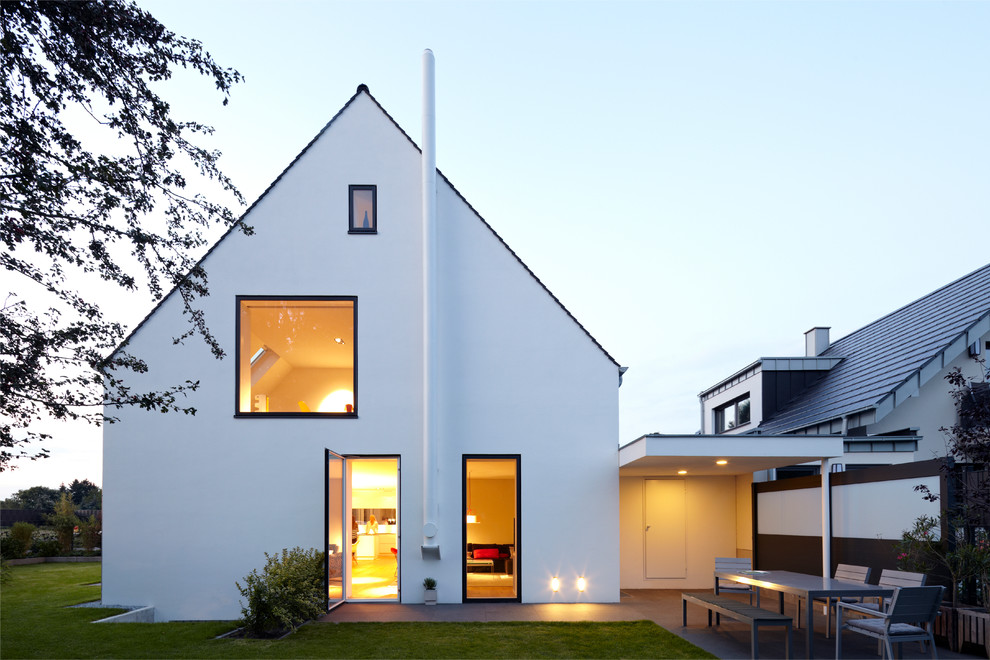 Imagen de fachada de casa blanca escandinava de tamaño medio de tres plantas con tejado a dos aguas y revestimiento de estuco