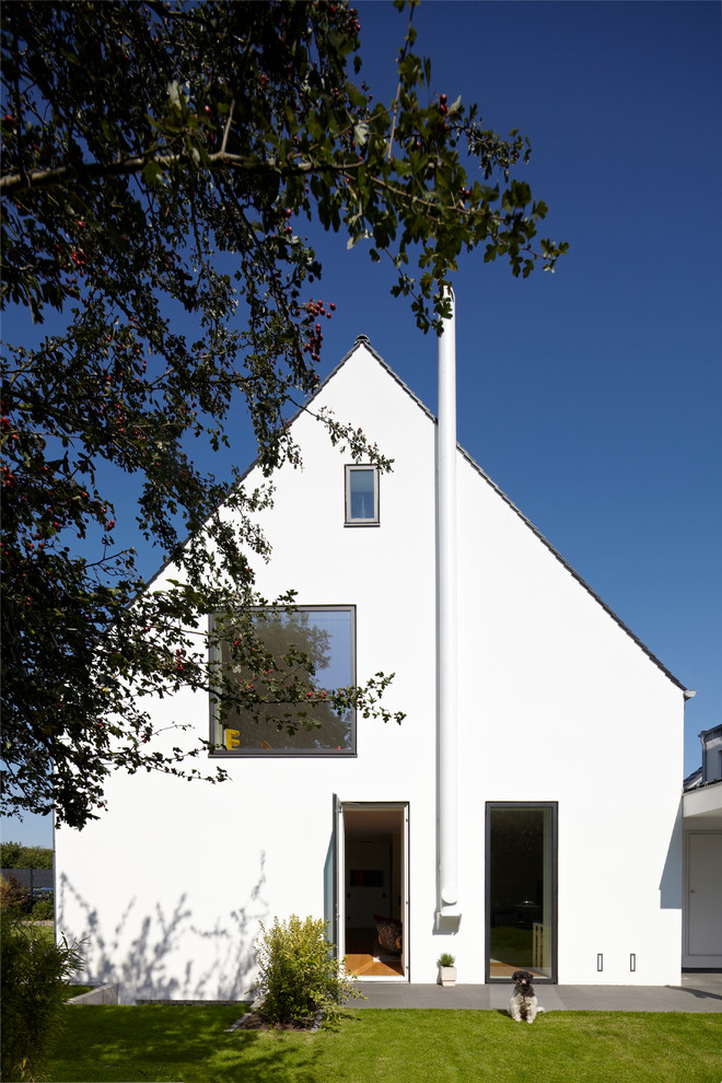 Diseño de fachada de casa blanca contemporánea con revestimiento de estuco y tejado a dos aguas
