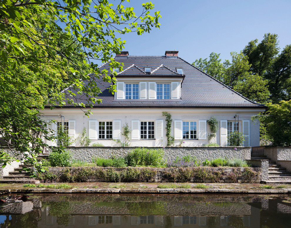 Mittelgroßes, Zweistöckiges Klassisches Haus mit weißer Fassadenfarbe und Mansardendach in München