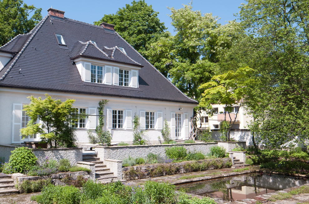 Imagen de fachada beige tradicional de tamaño medio de dos plantas con revestimiento de estuco y tejado a cuatro aguas