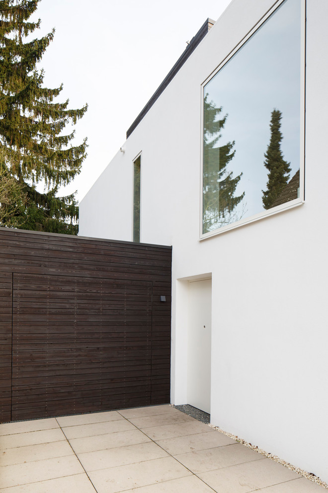 Modelo de fachada de casa blanca contemporánea de dos plantas con revestimiento de estuco y tejado plano