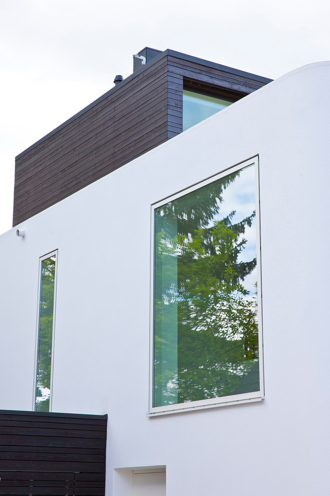 Imagen de fachada de casa blanca actual de dos plantas con revestimiento de estuco y tejado plano